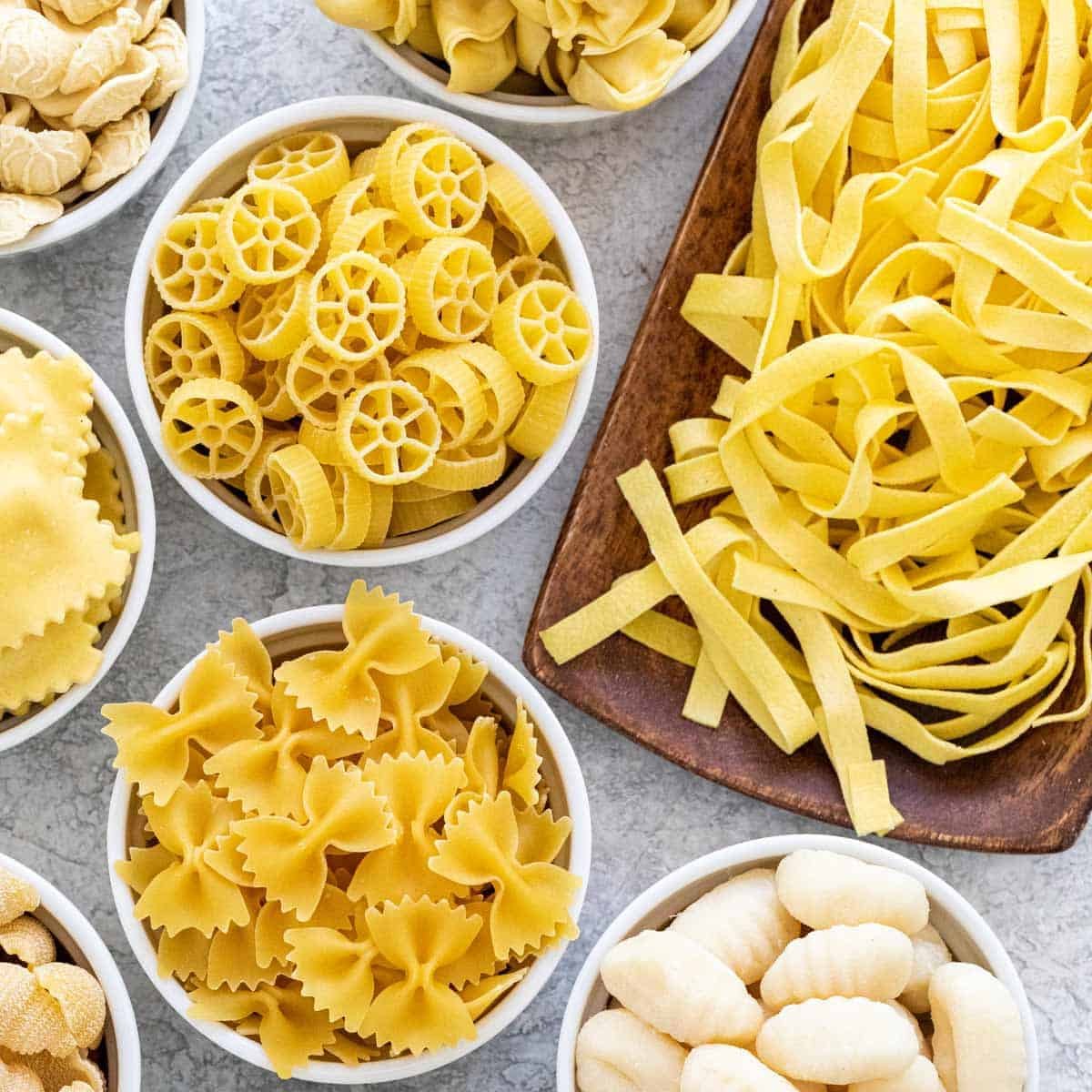 Assortment of dried pasta shapes in bowls